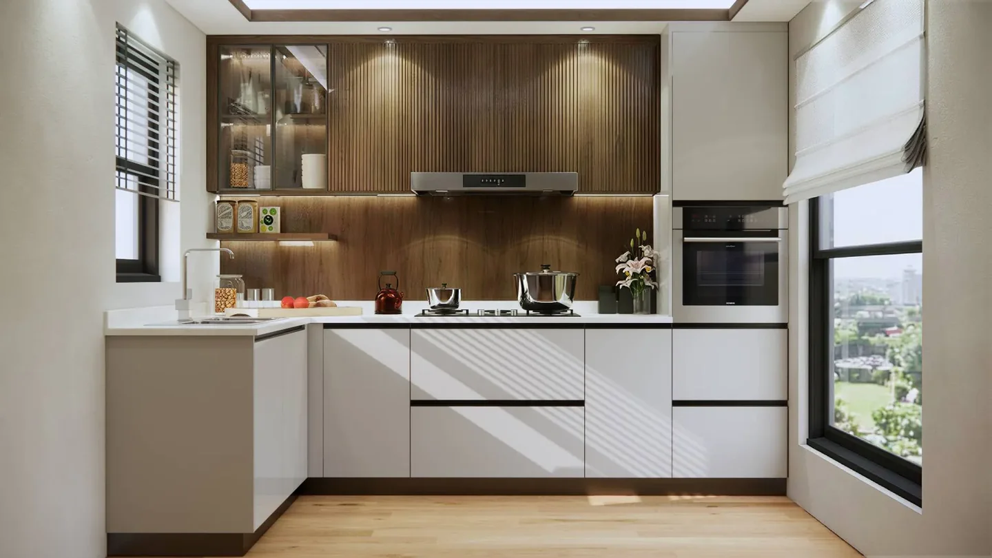 White L-shaped kitchen with fluted wood wall cabinets, illuminated glass storage and sunlight through window blinds.